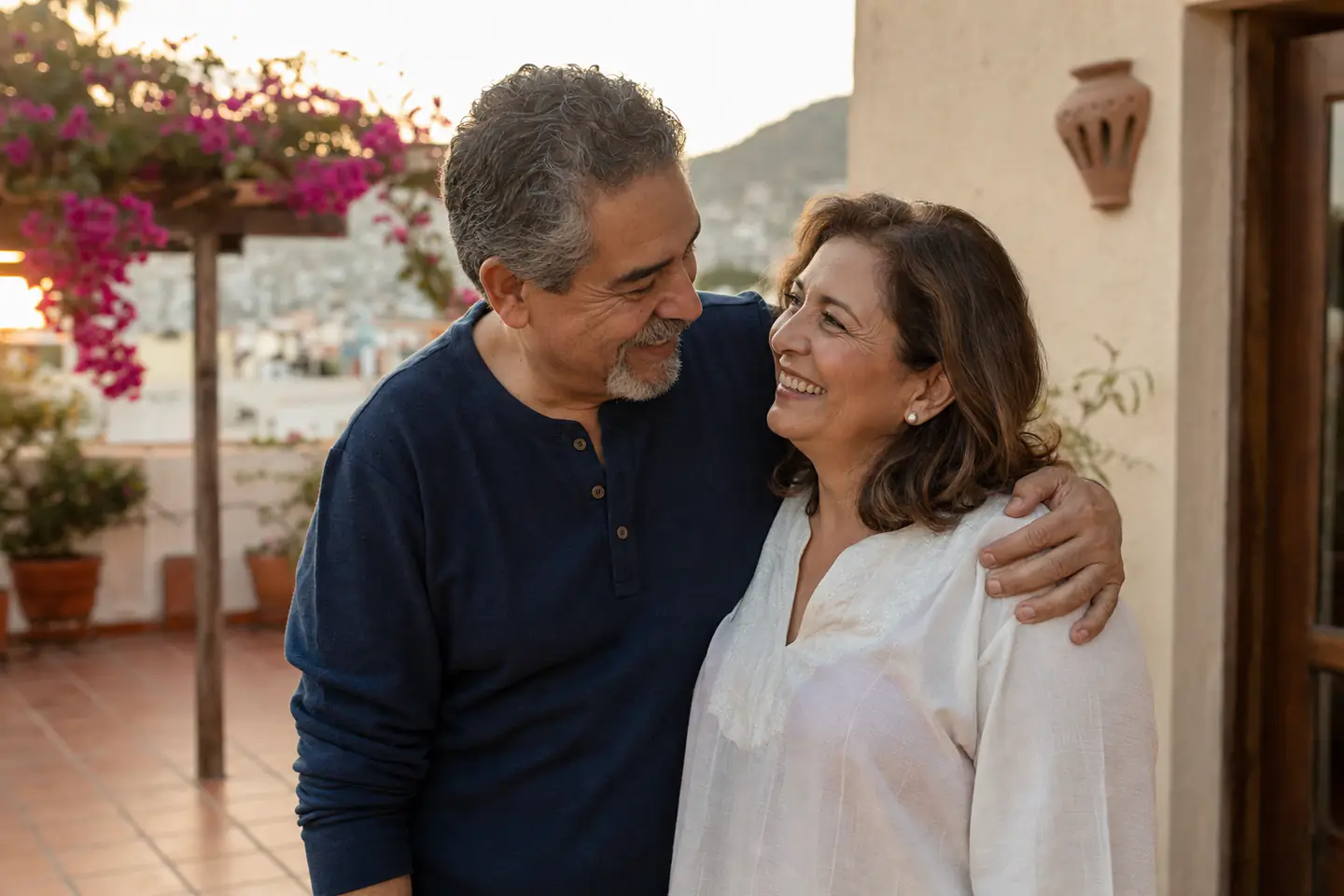 Pareja de más de 50 años abrazada en la terraza de su casa al atardecer